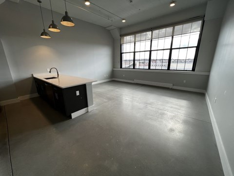 A large empty room with a desk and a window.
